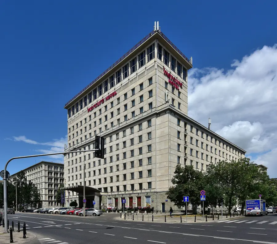 Jasny, wysoki gmach hotelu Mercure Warszawa Grand z czerwonym napisem pod dachem, widok z ulicy