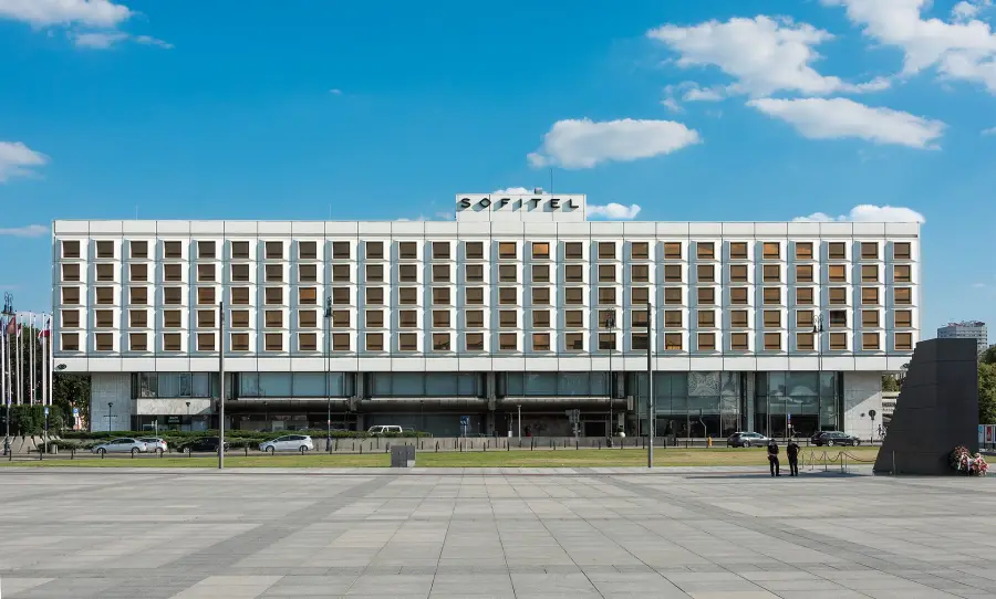 Długa biała fasada hotelu Sofitel Victoria z napisem na dachu, widok z placu Piłsudskiego